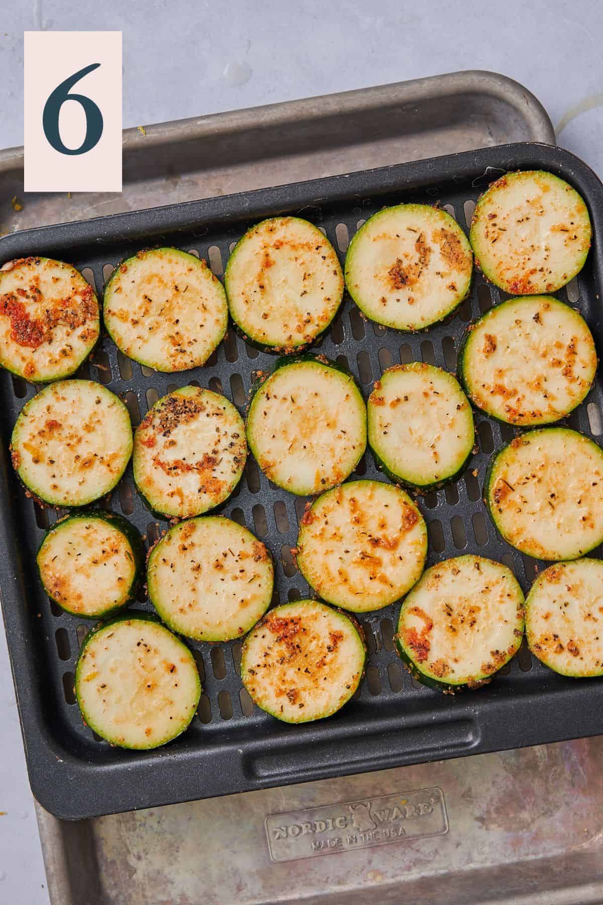 zucchini slices laid out in a single layer on air fryer tray.