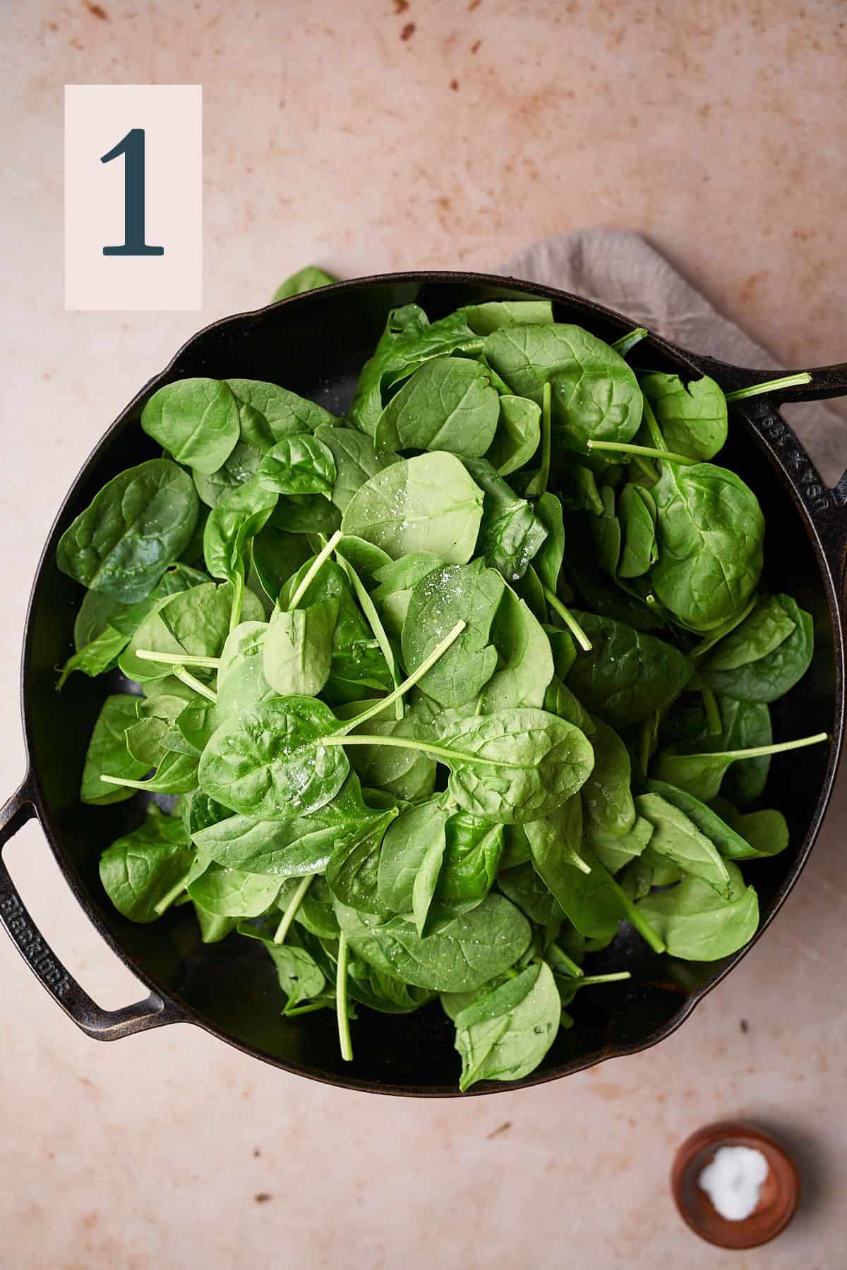 baby spinach in a skillet sprinkled with salt. 