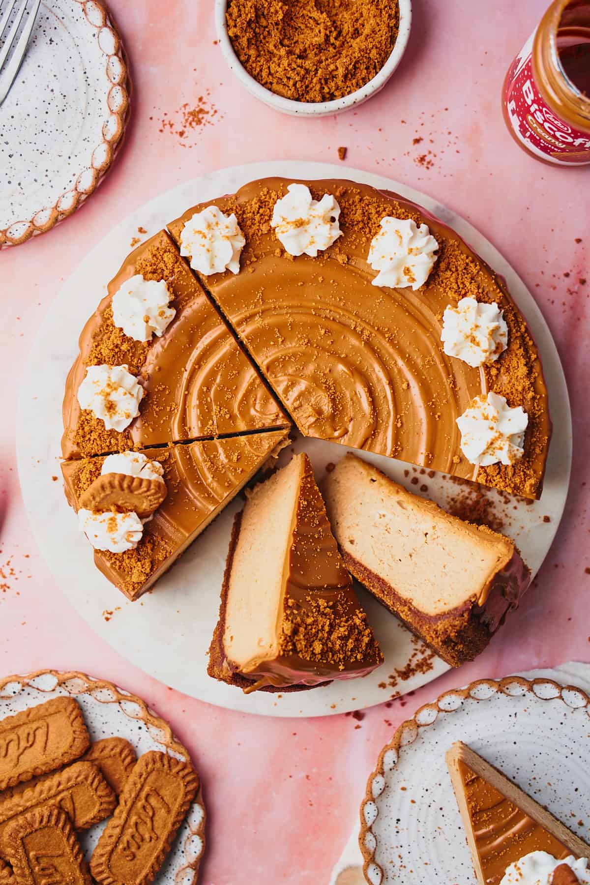 Lovely biscoff cheesecake topped with cookie butter, with some slices cut out, and dollops of whipped creak on the cheesecake. 