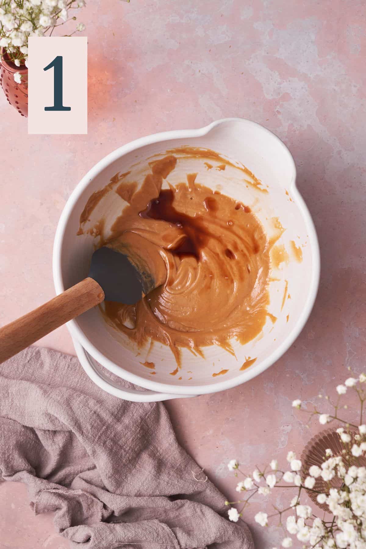 melted peanut butter and honey in a mixing bowl with vanilla extract. 
