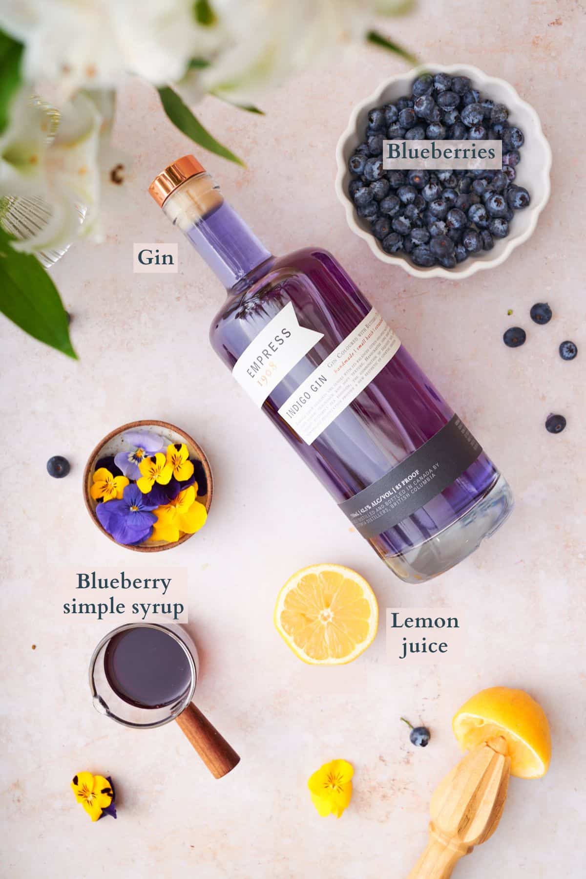 blueberry gin cocktail ingredients graphic, with items laid out in small bowls labeled to denote each ingredient. 
