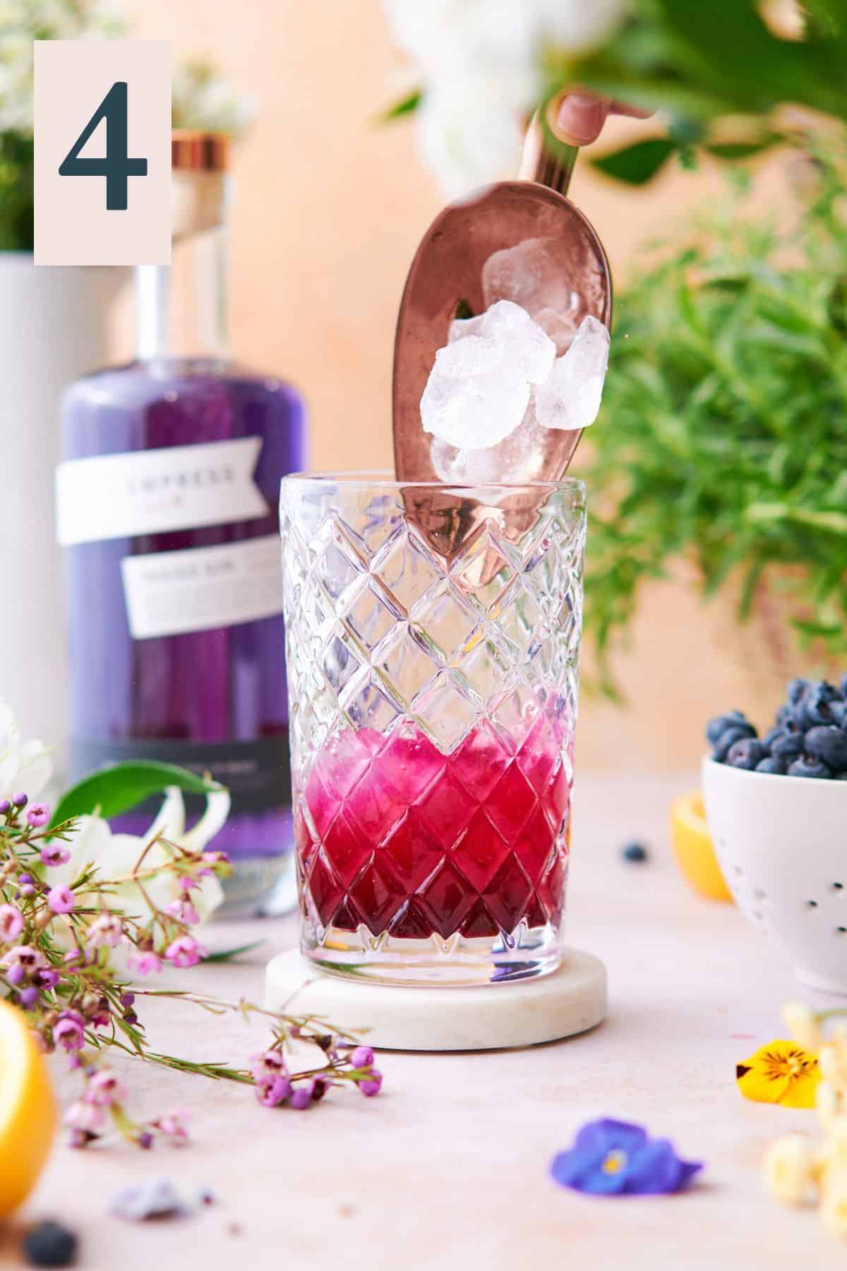 pouring ice into a cocktail shaker with a vibrant purple hue inside of the shaker. 