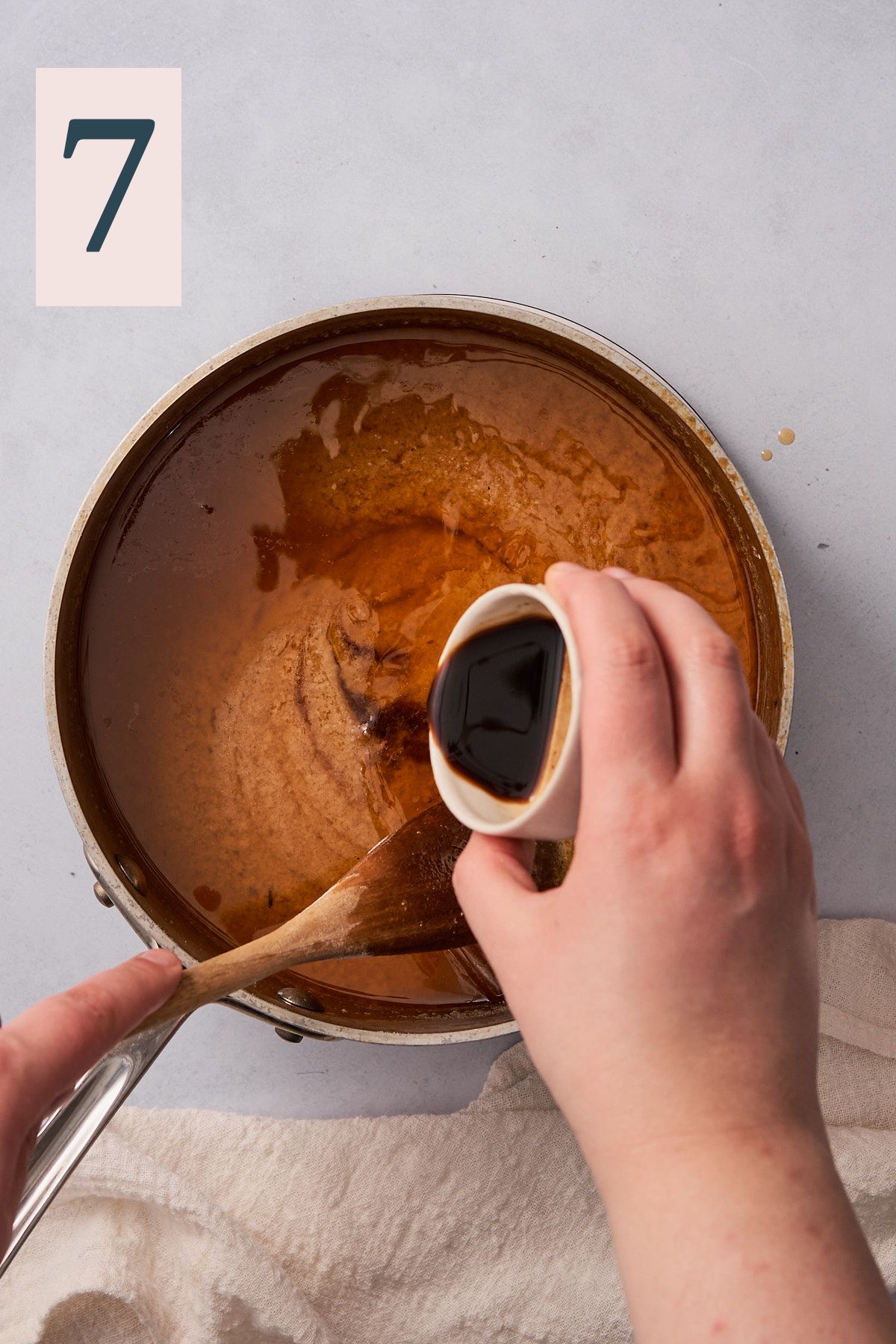 hand pouring Worcestershire sauce into a saucepan of gravy