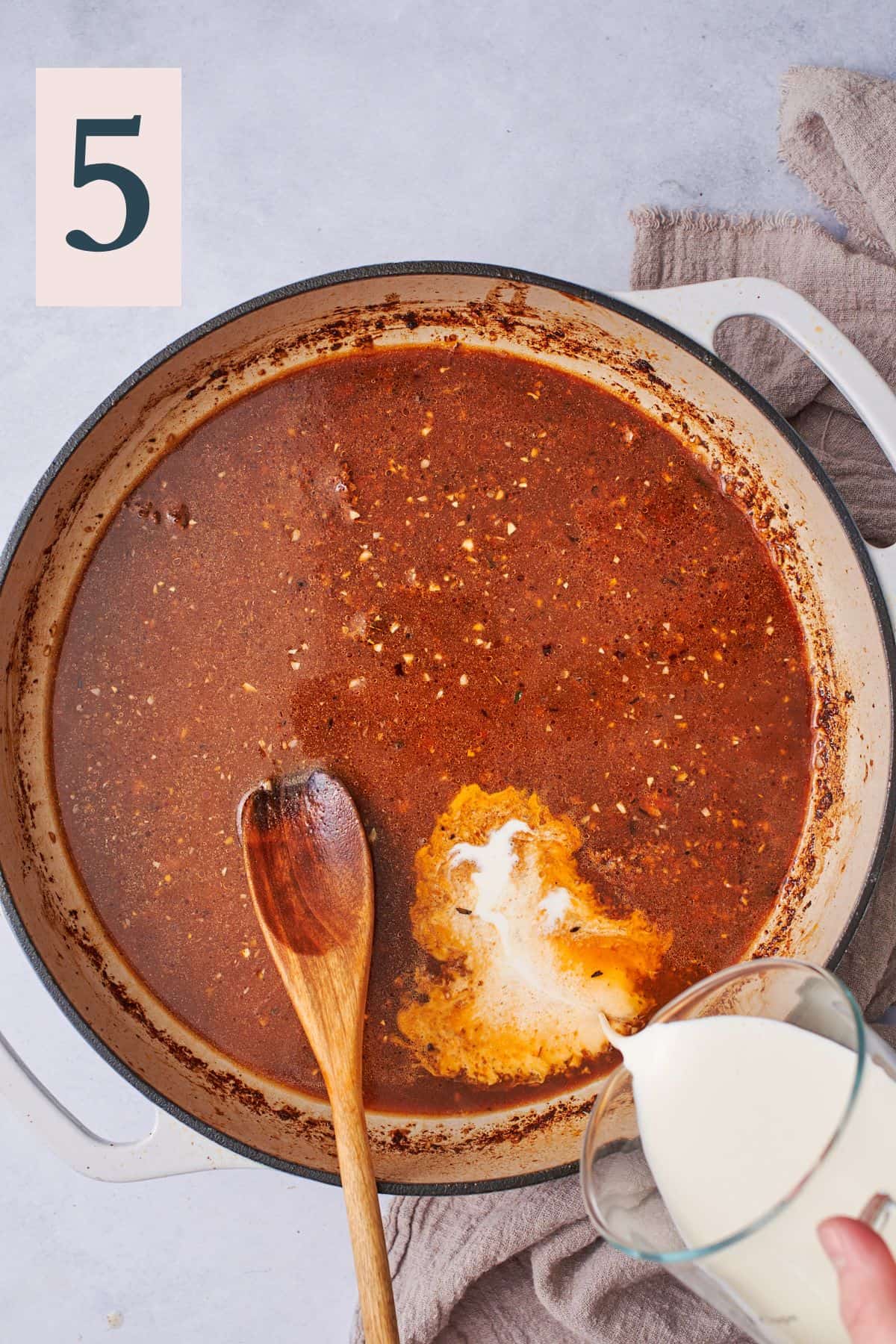 pouring cream into a spicy cajun broth in a skillet. 