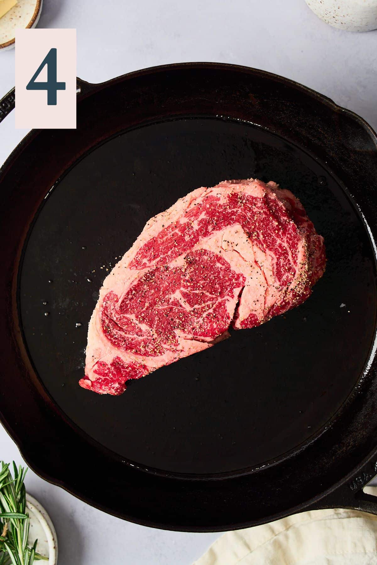 Raw seasoned steak in a hot cast iron skille.t 