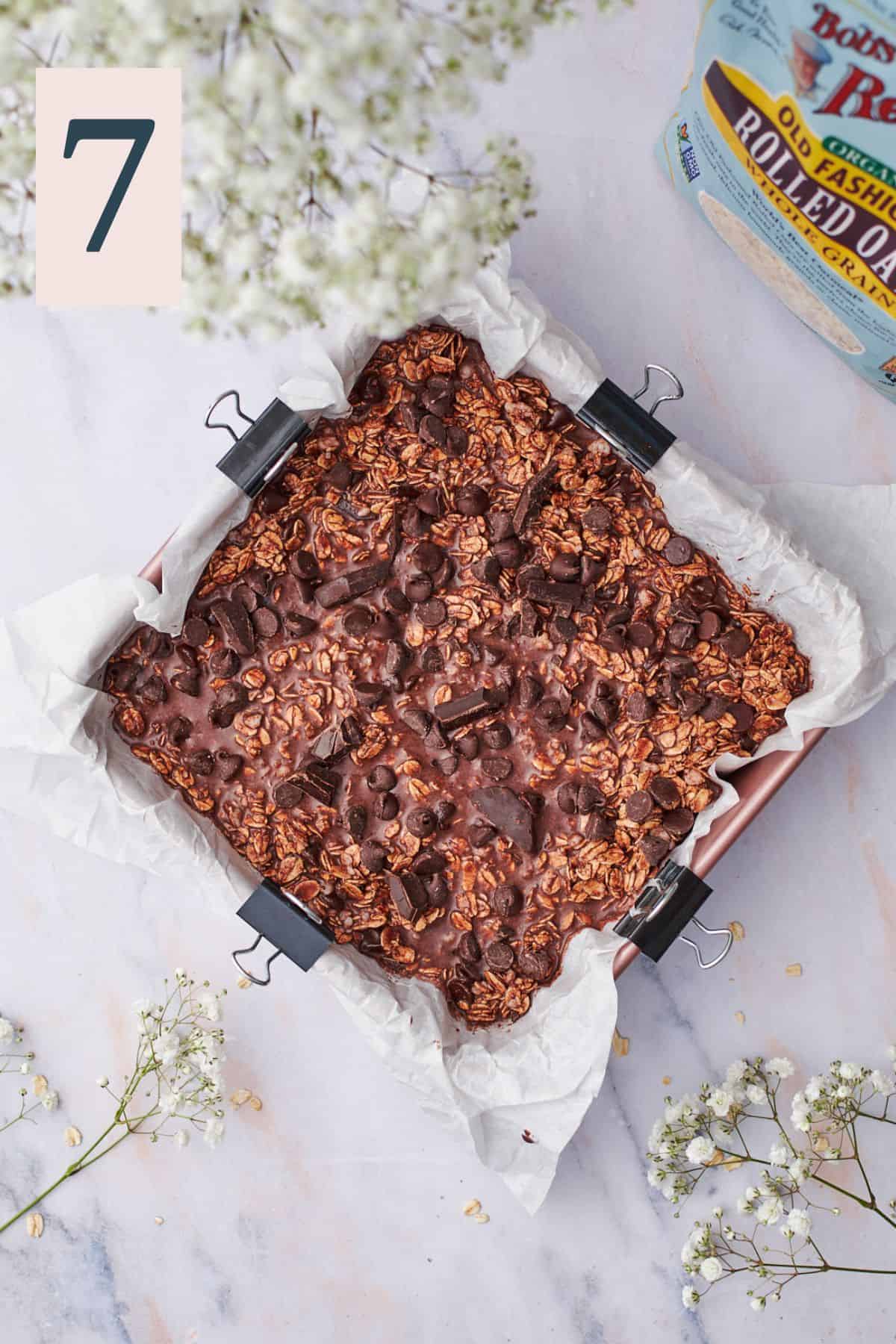 unbaked chocolate oats in a baking dish topped with chocolate chips and chunks. 