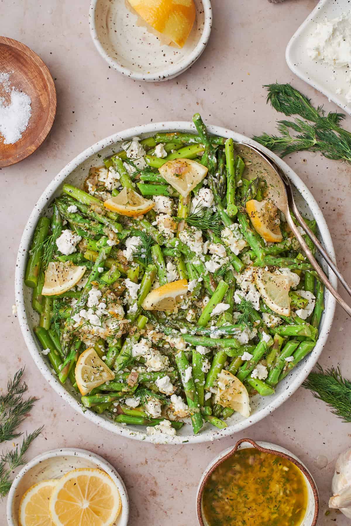 Cold asparagus salad with goat cheese, lemon, black pepper, and dill on a plate.