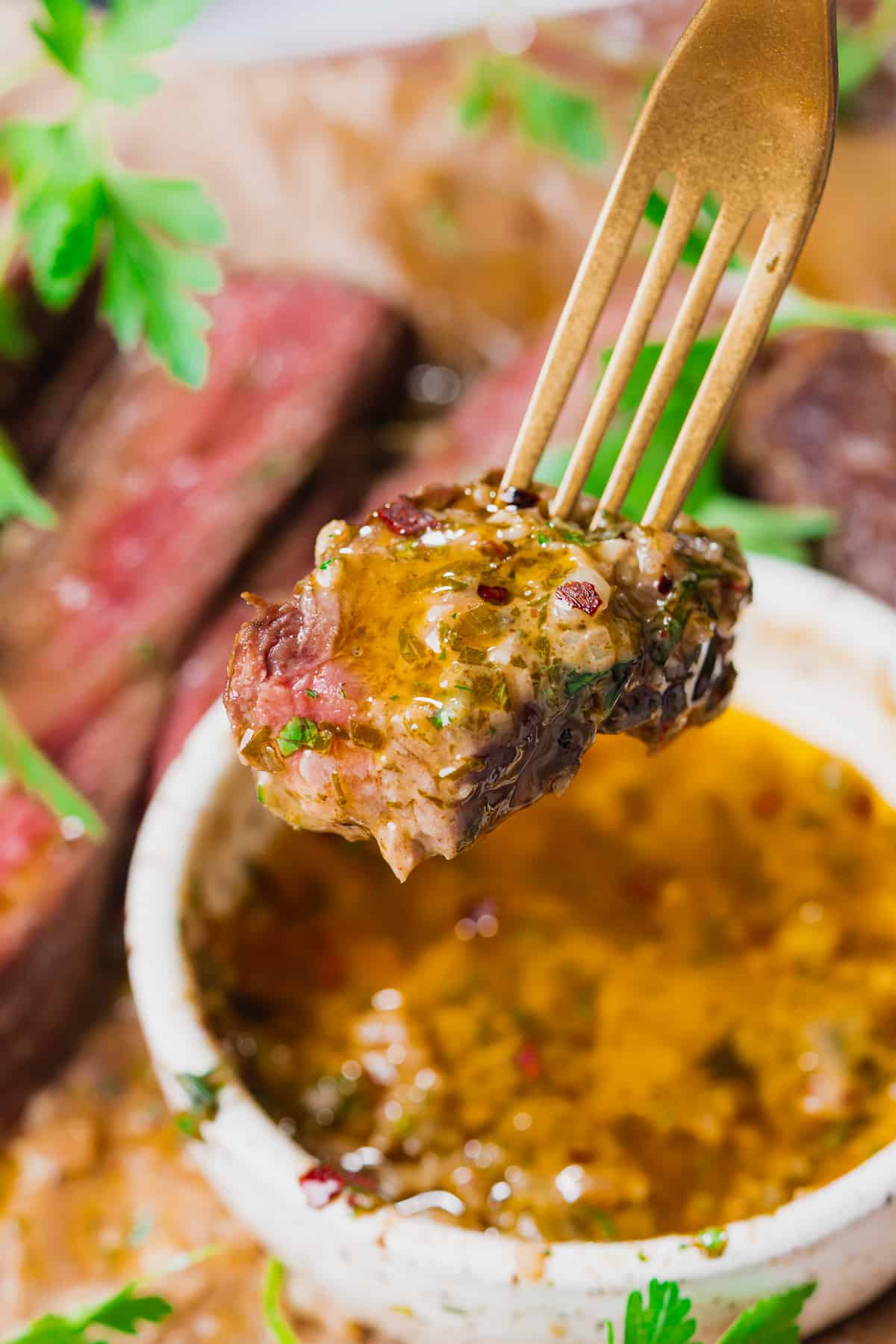 delicious photo of medium rare steak dipped in cowboy butter dipping sauce on a fork. 