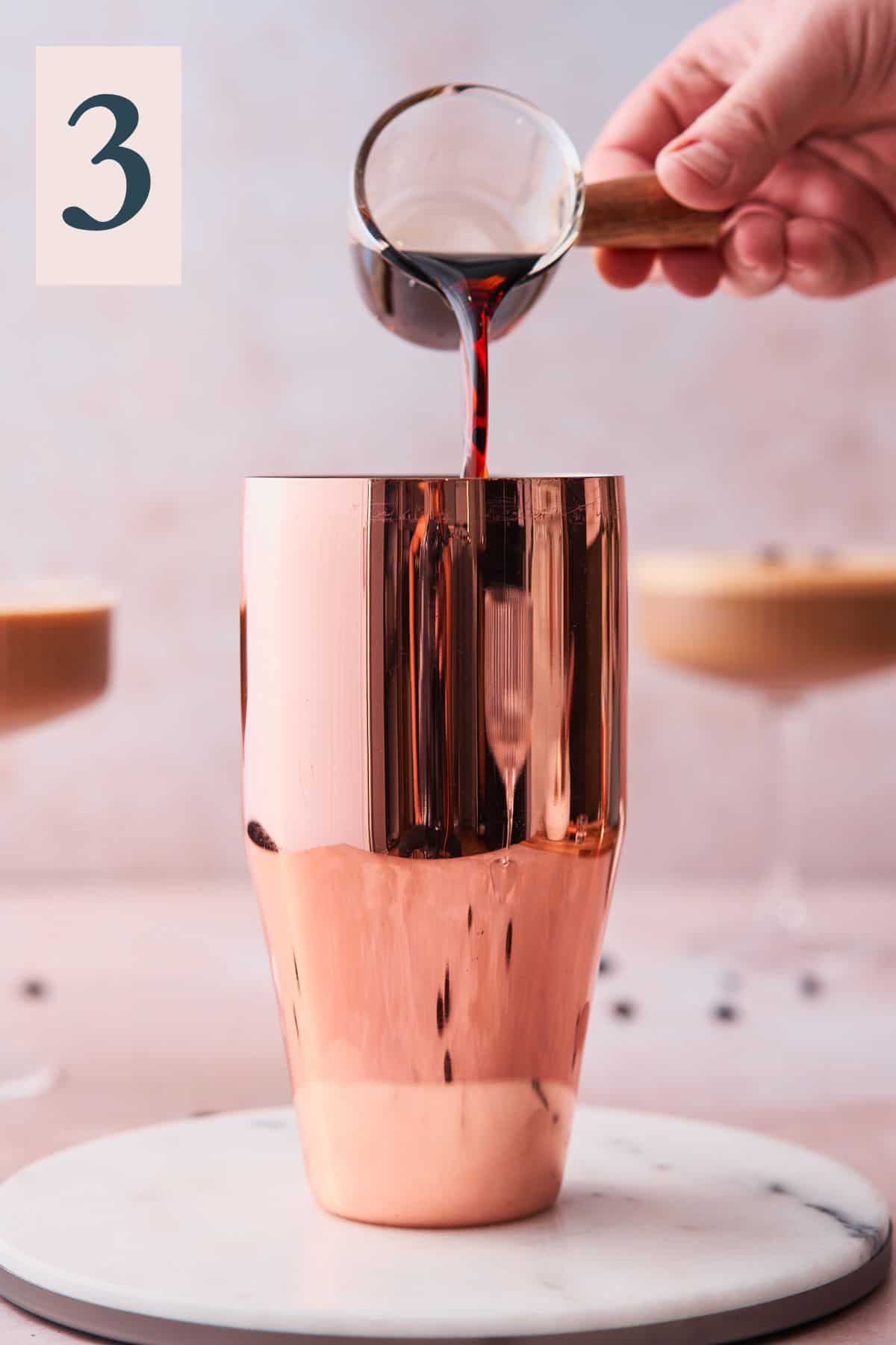 hand pouring in coffee liqueur into a cocktail shaker surrounded by espresso martinis. 