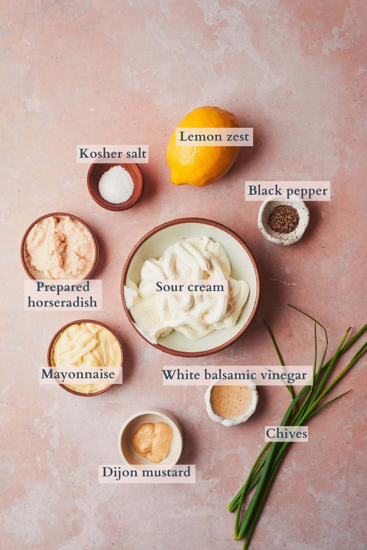 Ingredients to make creamy horseradish sauce laid out on a table and labeled to denote each ingredient.