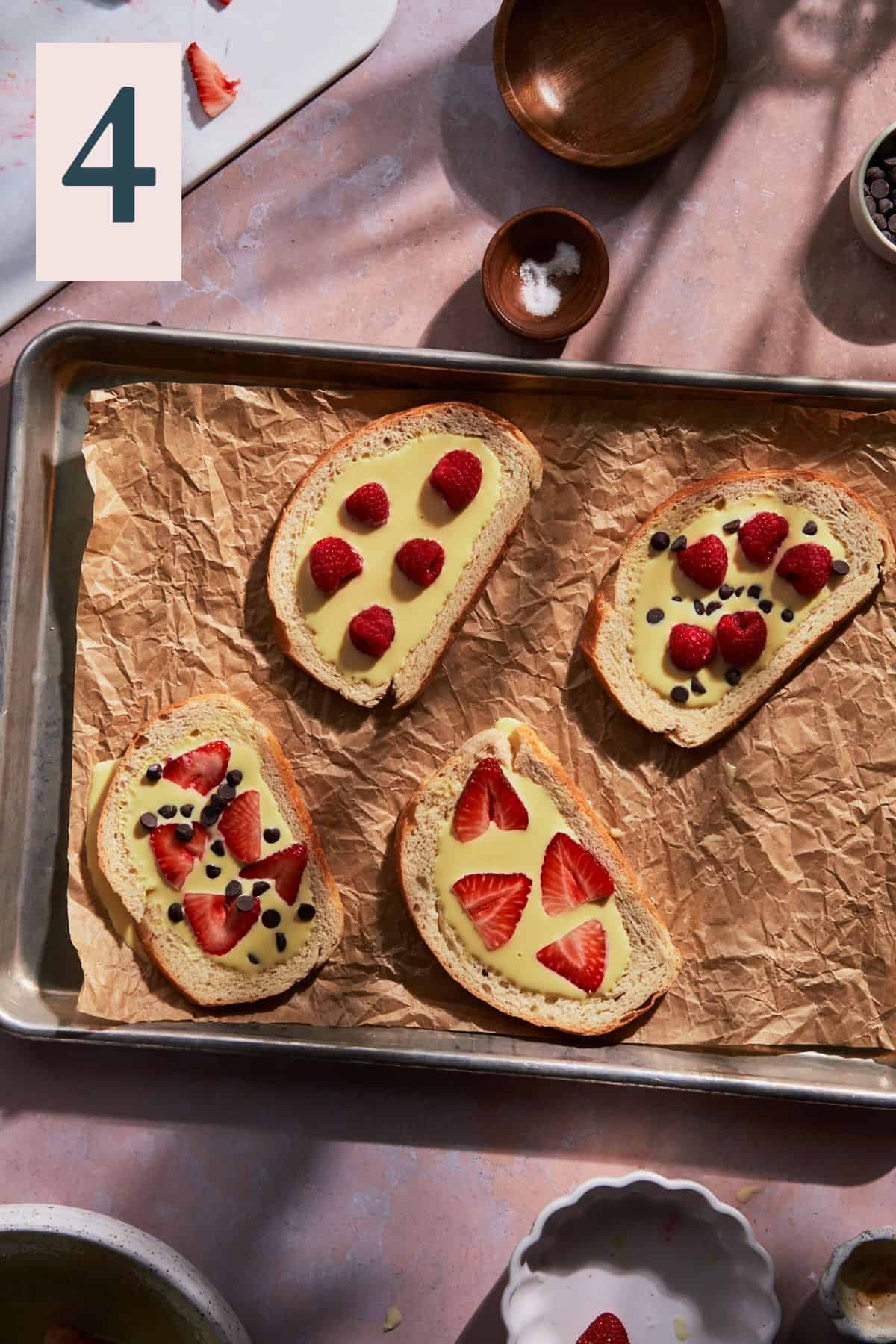 Topping custard toast with chocolate chips, strawberries, and raspberries before baking.