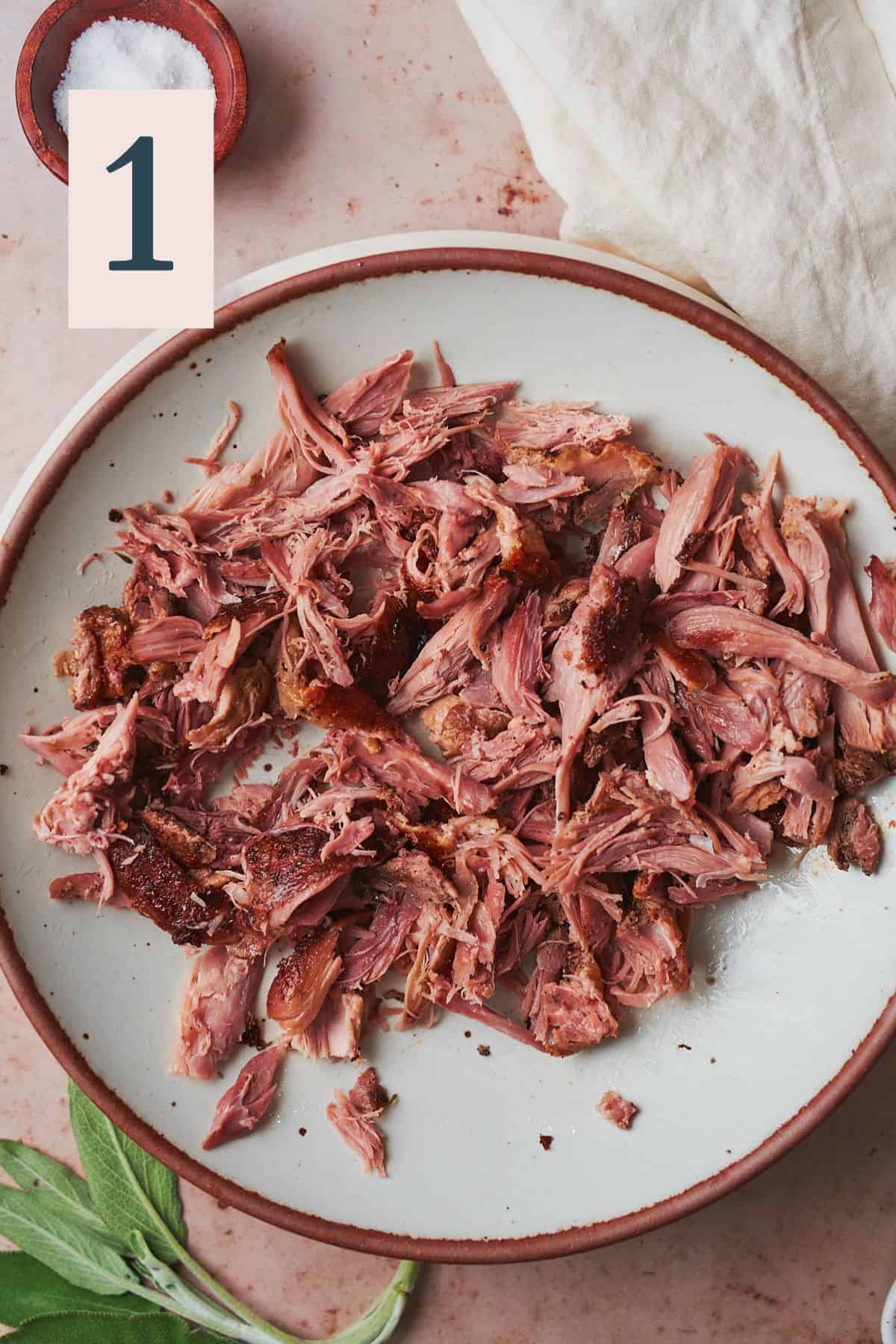Shredded and cooked duck meat on a plate. 