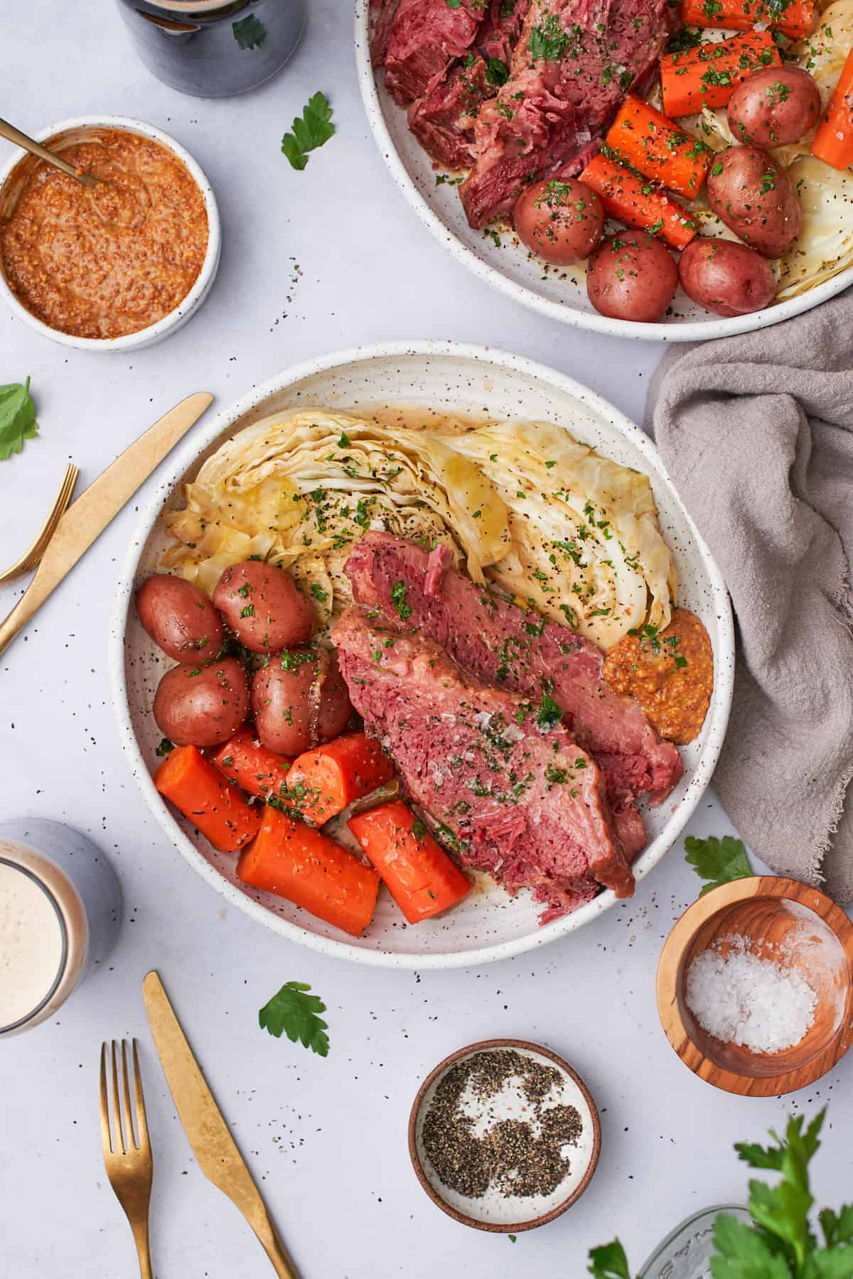 overhead shot of corned beef with potatoes, carrots, cabbage, stone ground mustard, parsley, and guinness on the side. 
