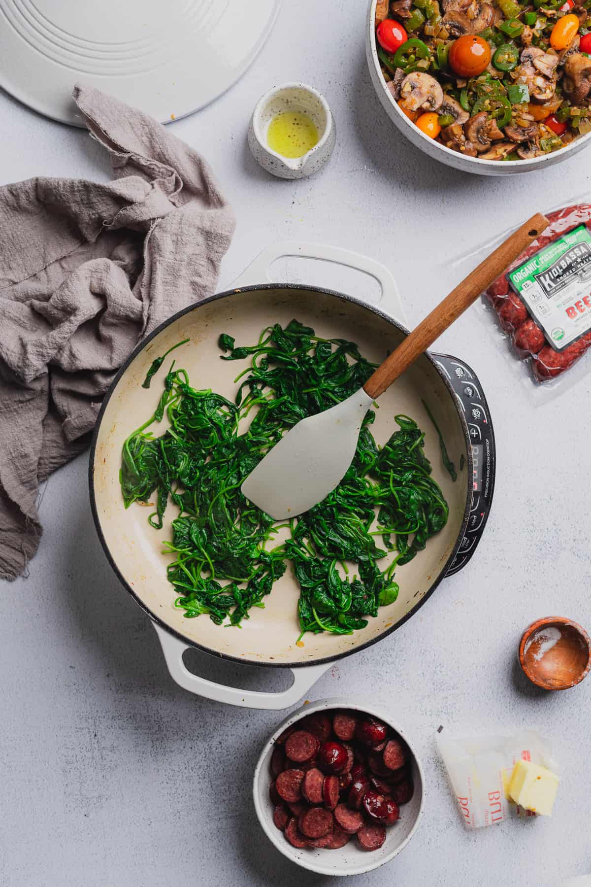 wilting spinach in an enameled dutch oven with a rubber spatula