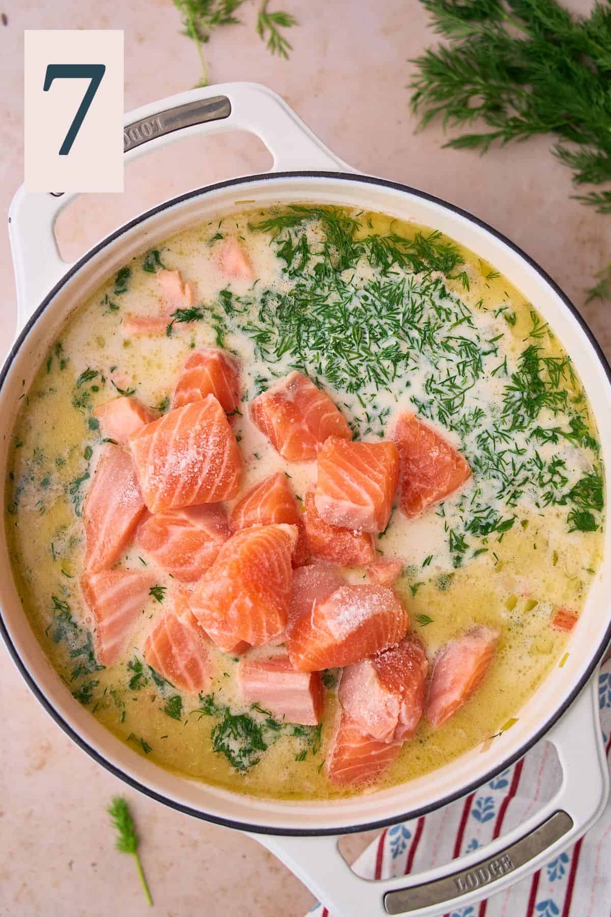 Raw salmon added to a soup pot with heavy cream, and dill added. 