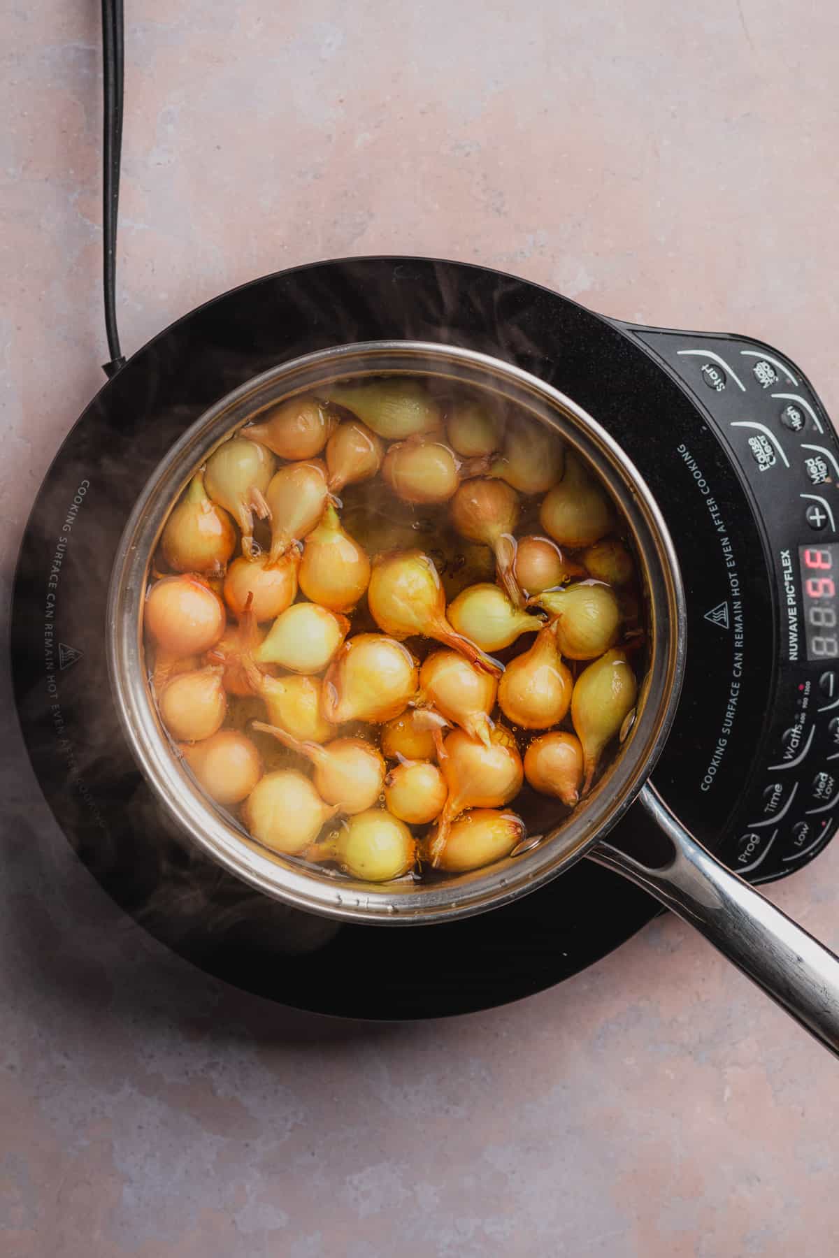 gold pearl onions in a saucepan of boiling water