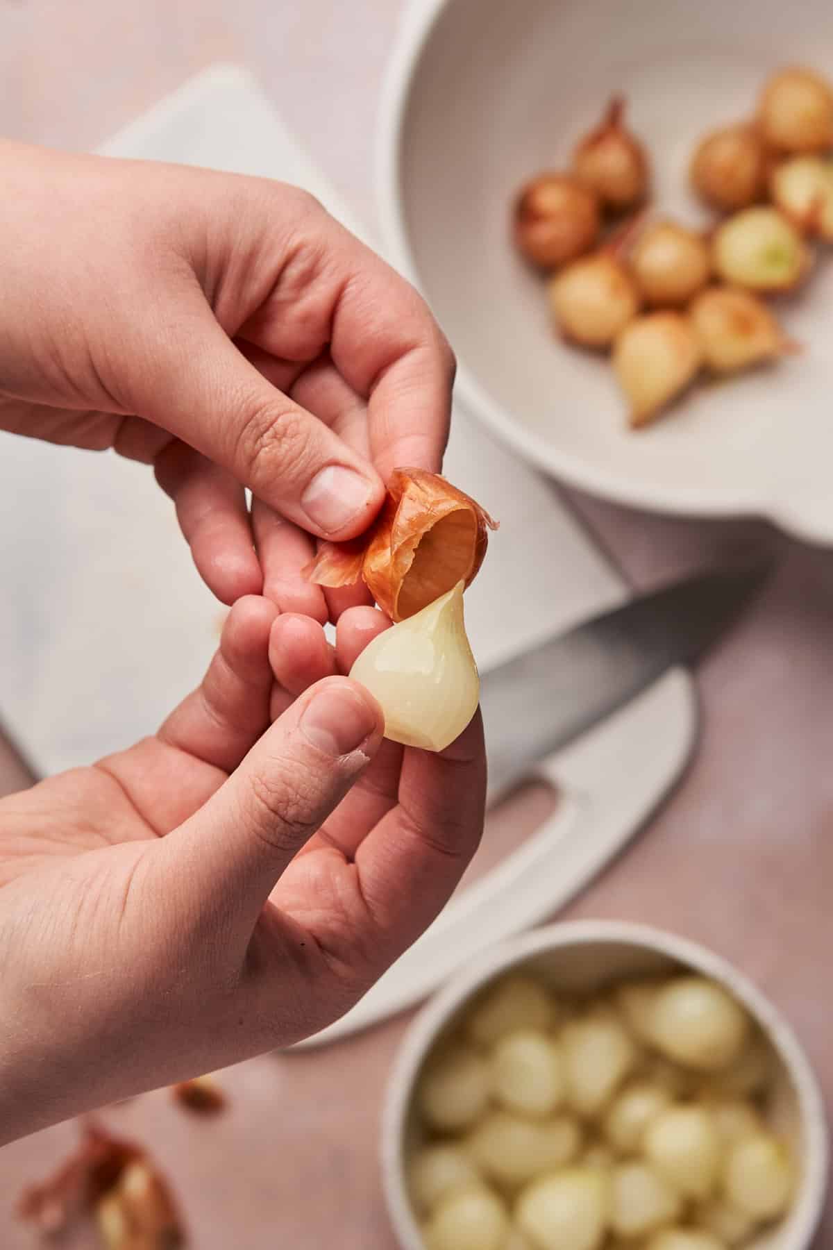 hands holding a pearl onion and peeling the skin off 