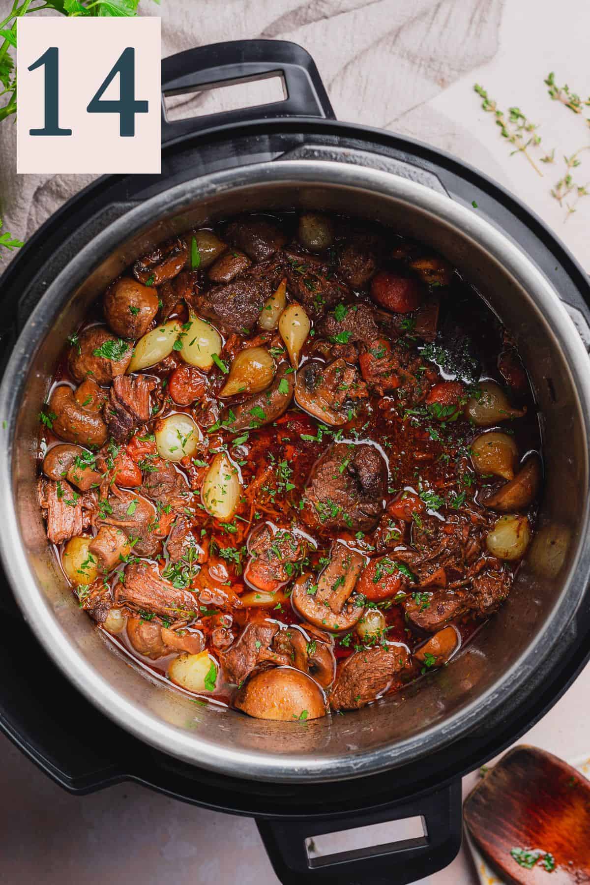 beef bourguignon in a pressure cooker topped with fresh parsley and thyme.