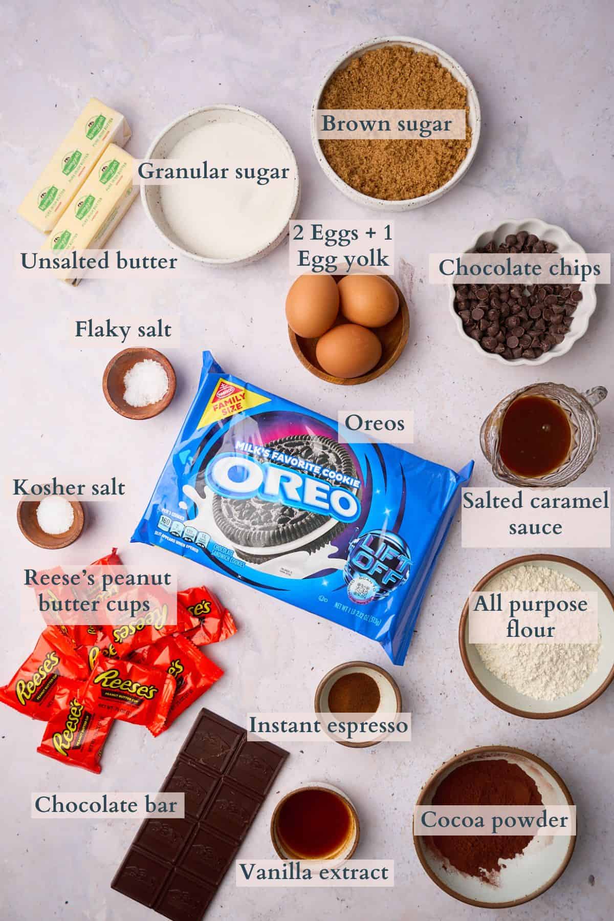 Ingredients to make loaded brownies laid out on a table and labeled to denote each ingredient. 