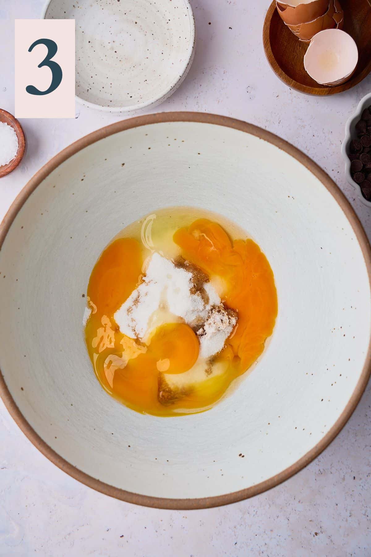 Eggs and and egg yolk in a bowl with brown and white sugar. 