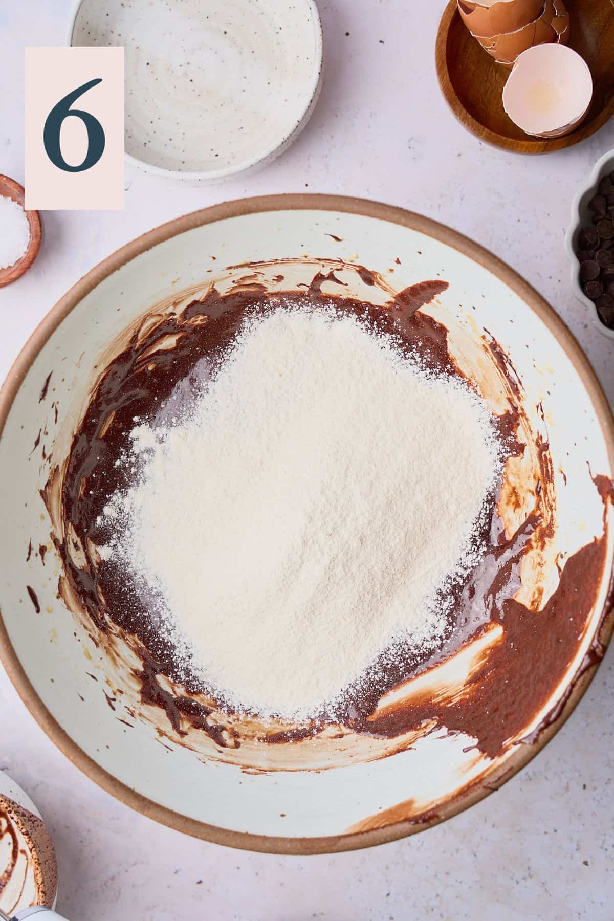 Flour and salt added to brownie batter in a large bowl. 