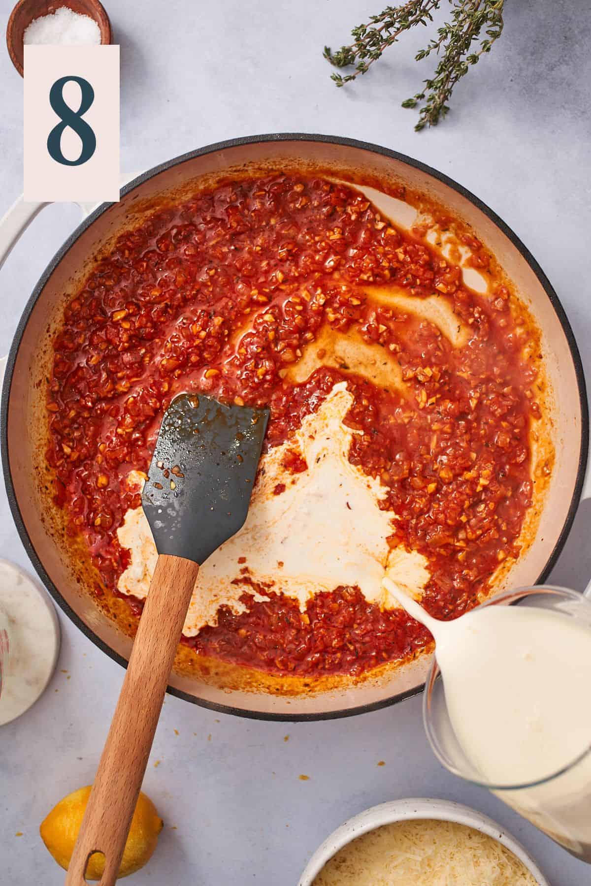 pouring heavy cream into an enameled skillet with shallots and tomato paste. 