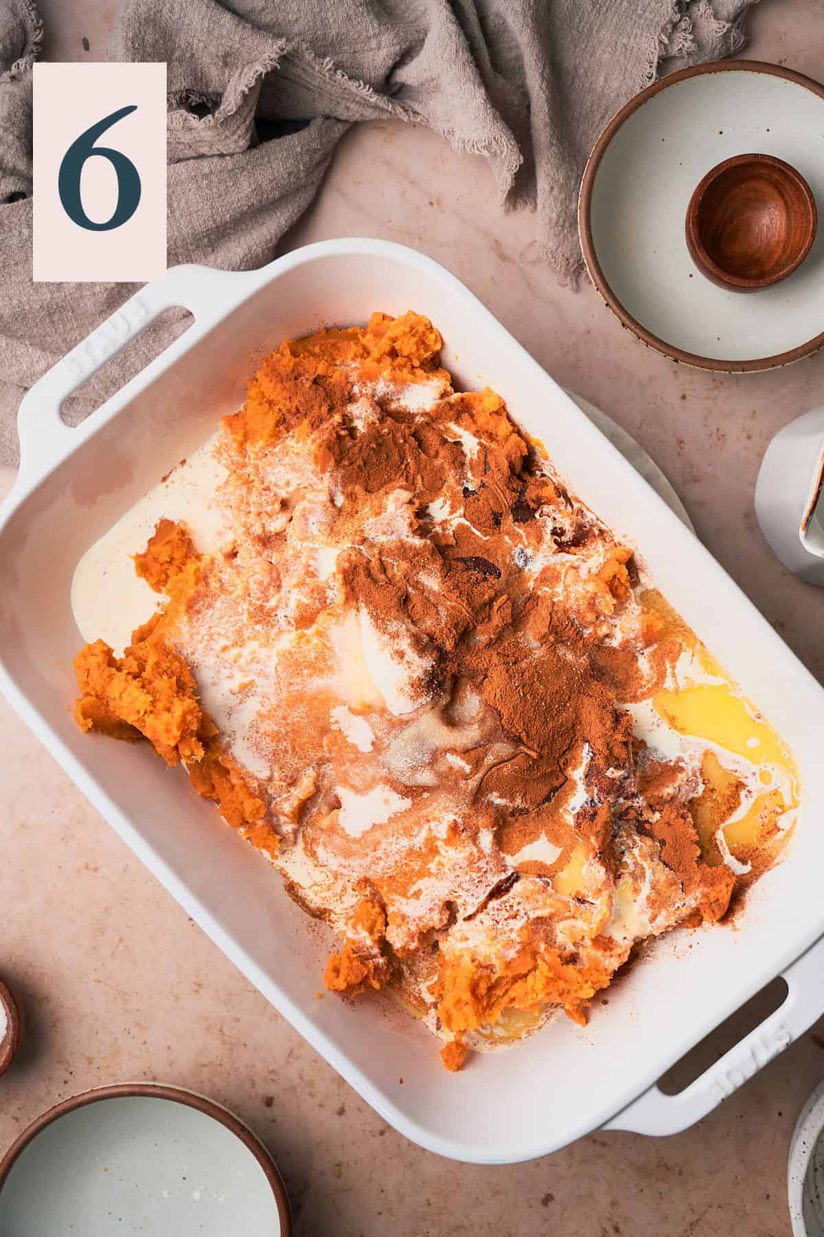 mashed sweet potatoes in a large baking dish with cream, butter, sugar, and cinnamon. 