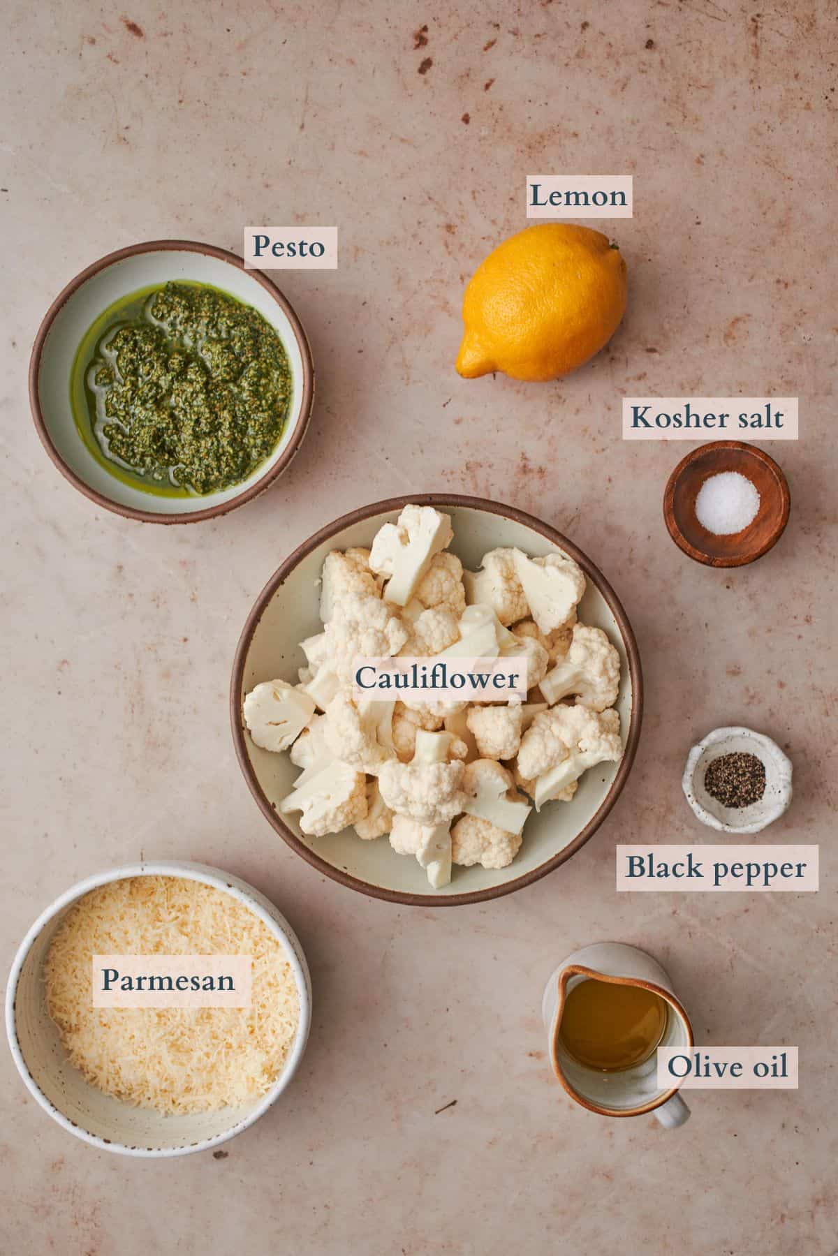 ingredients to make pesto cauliflower in small bowls laid out and labeled to denote each ingredient. 