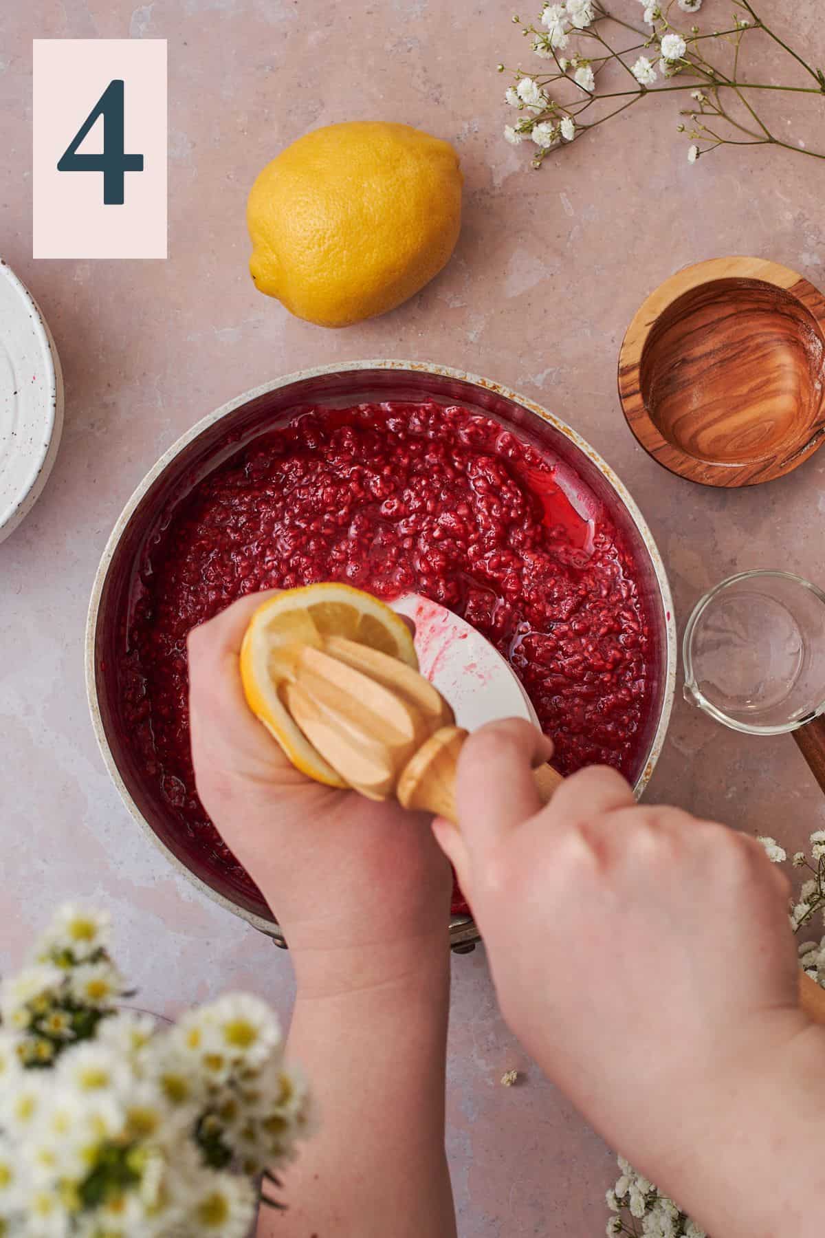 hand squeezing fresh lemon juice into a saucepan of raspberry compote. 