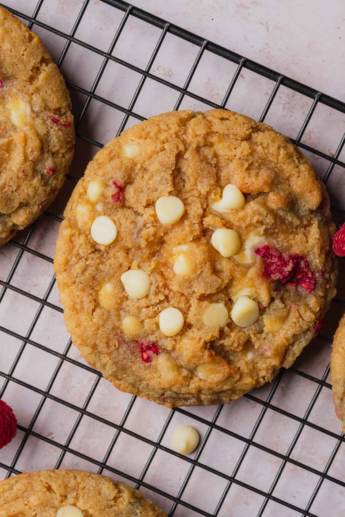 close up shot of a large raspberry white chocolate cookie on a black cooling rack