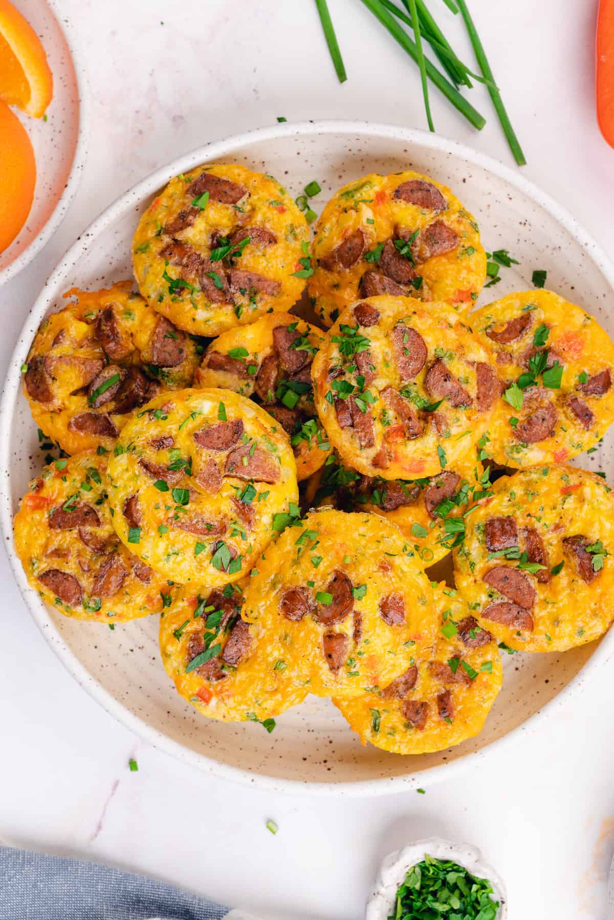 plate full of sausage and egg muffins topped with parsley and chives