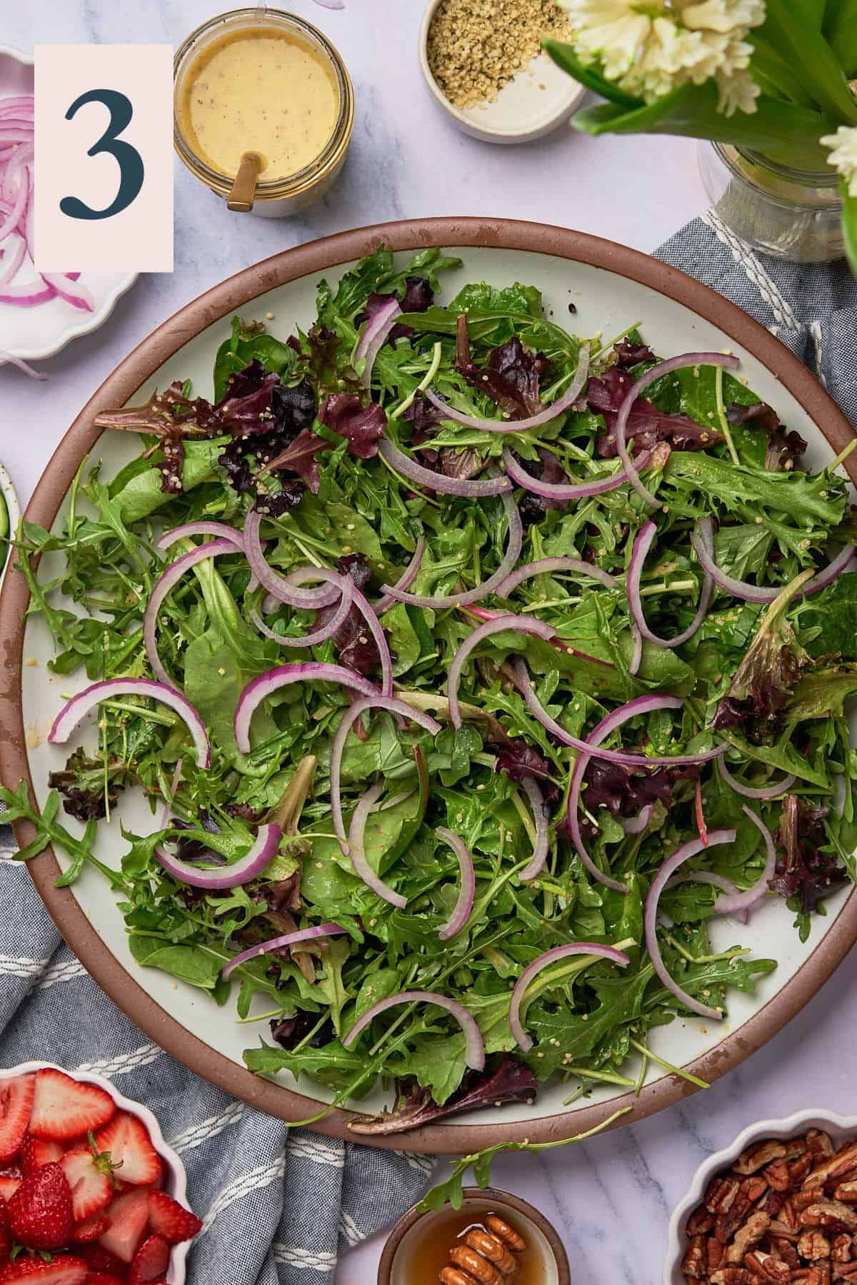 Red onions topping plate of arugula.