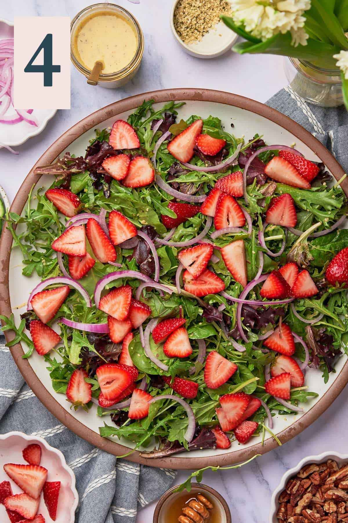 Arugula salad topped with strawberry halves.