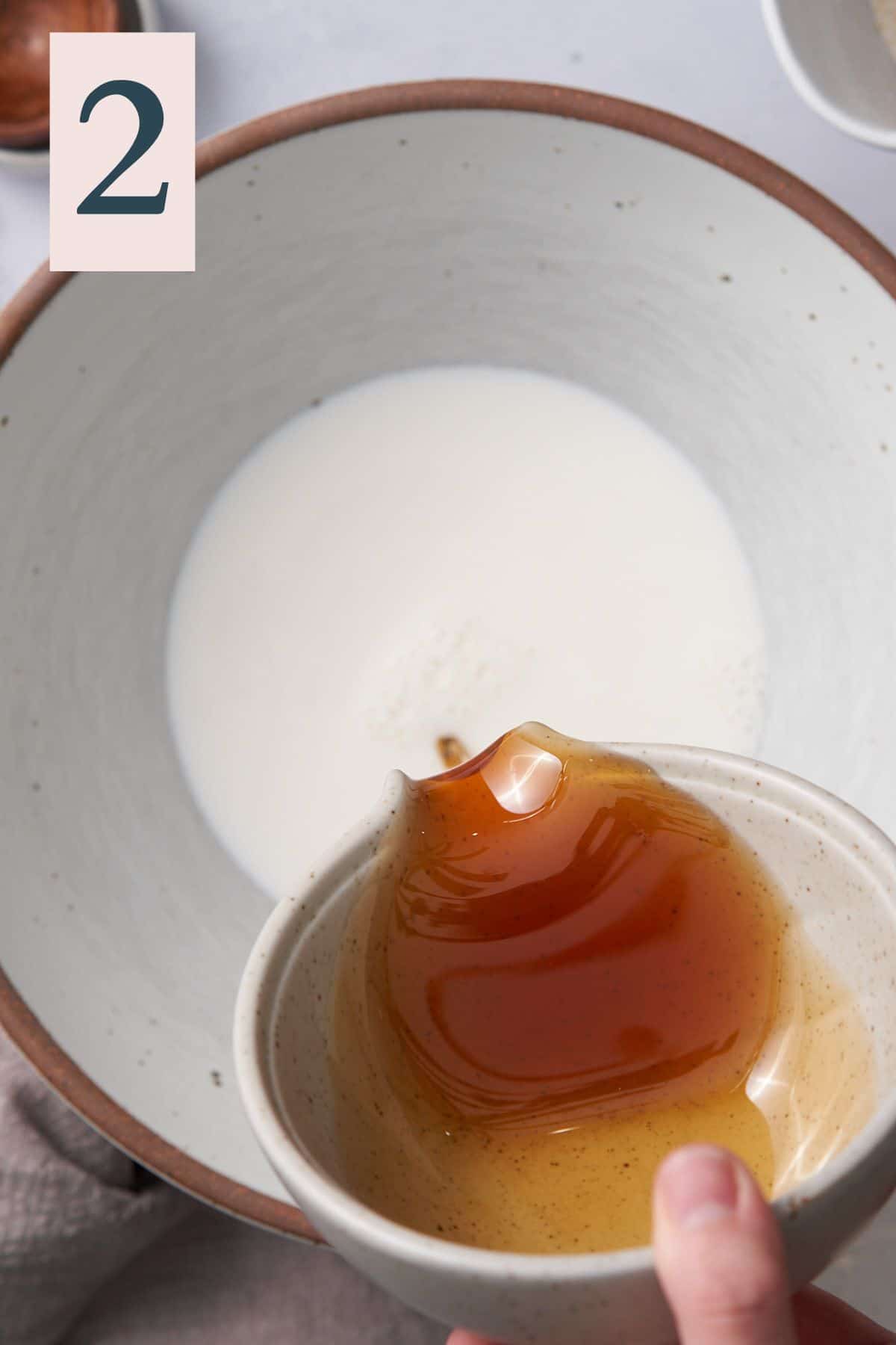 pouring honey into a large bowl with milk. 