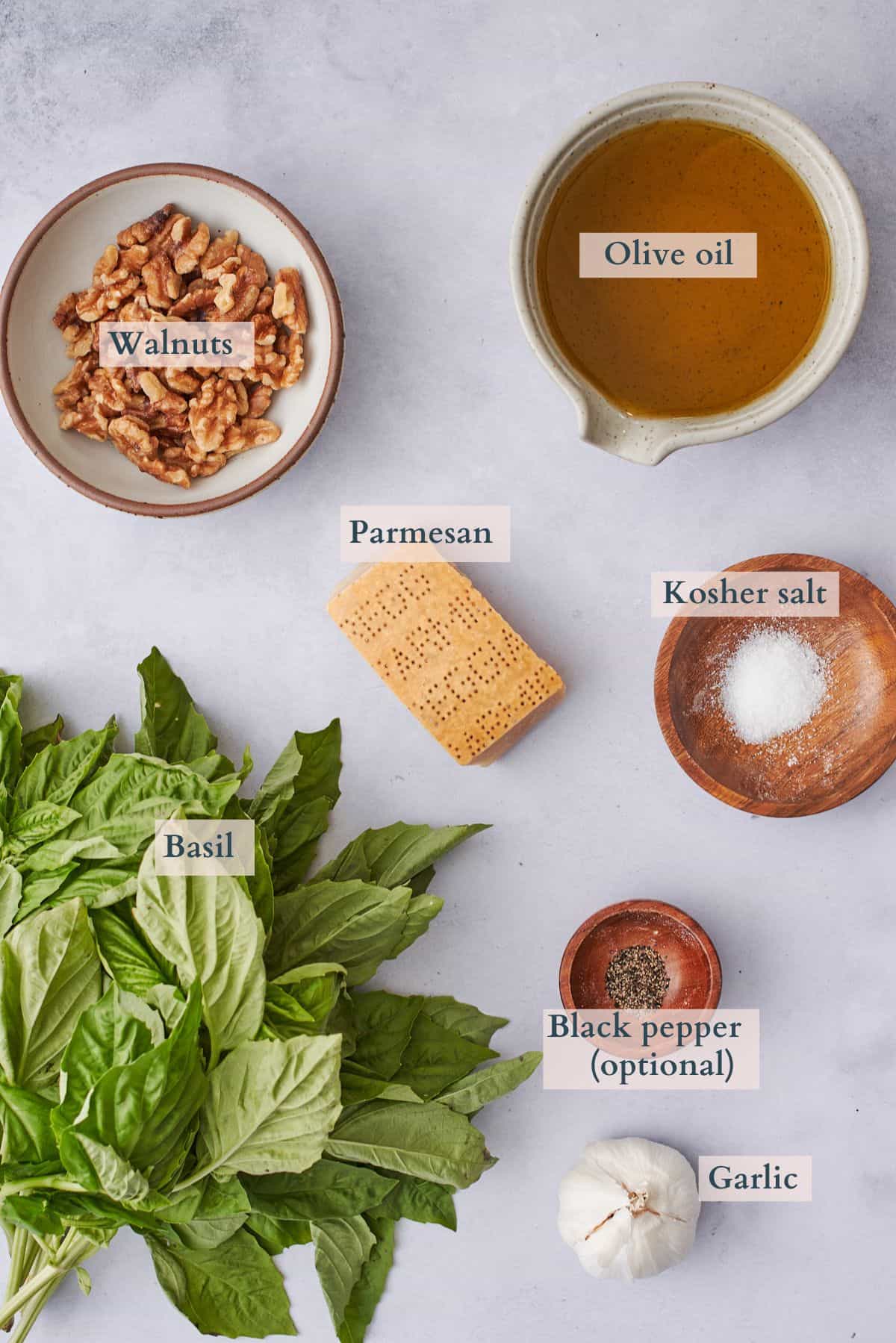 Ingredients to make walnut pesto with text overlaying to denote each ingredient. 
